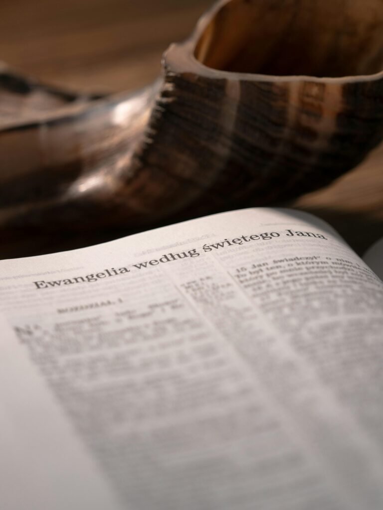 Close-up of an open Polish Bible with the text of Saint John. A shofar horn is blurred in the background.